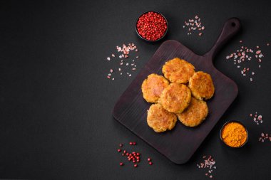 Delicious hearty vegetarian or vegan dish in the form of cutlets or patties consisting of potatoes, carrots, onions and beans on a dark concrete background