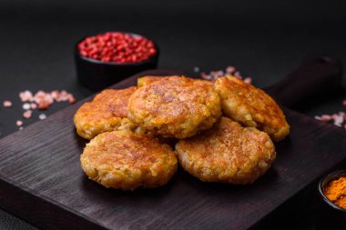 Delicious hearty vegetarian or vegan dish in the form of cutlets or patties consisting of potatoes, carrots, onions and beans on a dark concrete background