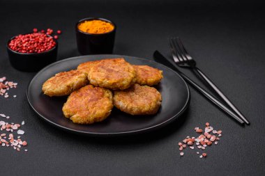 Delicious hearty vegetarian or vegan dish in the form of cutlets or patties consisting of potatoes, carrots, onions and beans on a dark concrete background