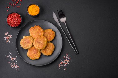 Delicious hearty vegetarian or vegan dish in the form of cutlets or patties consisting of potatoes, carrots, onions and beans on a dark concrete background
