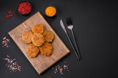Delicious hearty vegetarian or vegan dish in the form of cutlets or patties consisting of potatoes, carrots, onions and beans on a dark concrete background