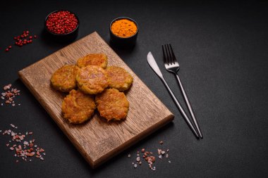 Delicious hearty vegetarian or vegan dish in the form of cutlets or patties consisting of potatoes, carrots, onions and beans on a dark concrete background