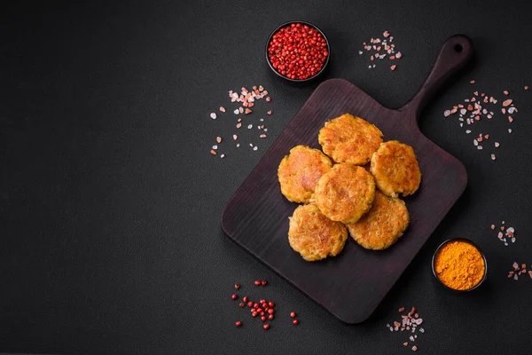 Delicious hearty vegetarian or vegan dish in the form of cutlets or patties consisting of potatoes, carrots, onions and beans on a dark concrete background