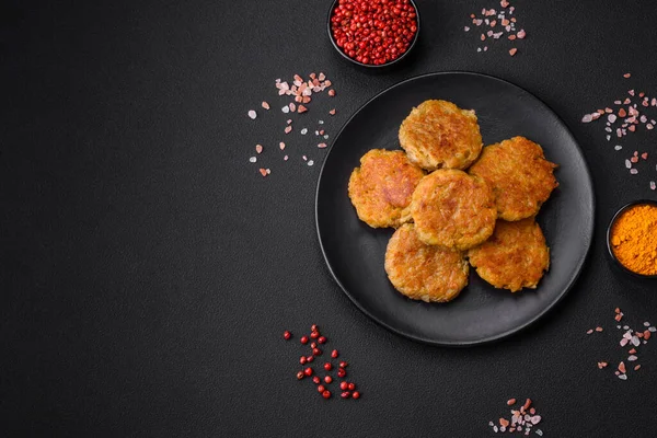 Delicious hearty vegetarian or vegan dish in the form of cutlets or patties consisting of potatoes, carrots, onions and beans on a dark concrete background