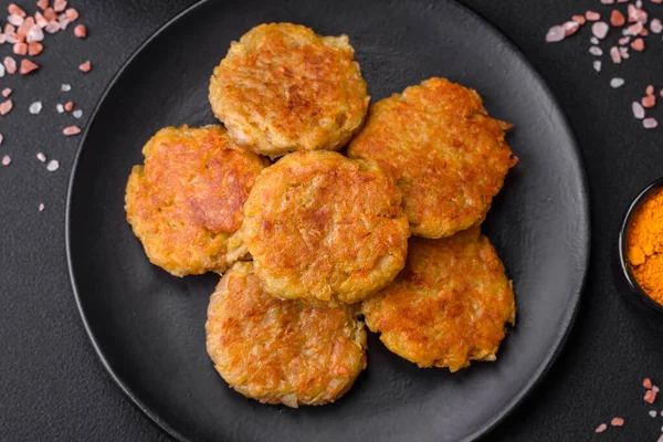 Delicious hearty vegetarian or vegan dish in the form of cutlets or patties consisting of potatoes, carrots, onions and beans on a dark concrete background