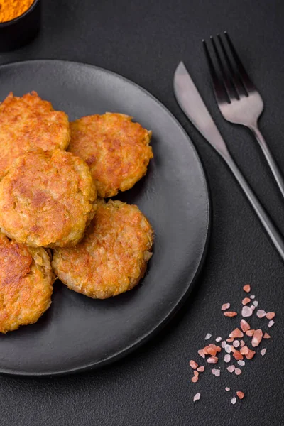 Delicious hearty vegetarian or vegan dish in the form of cutlets or patties consisting of potatoes, carrots, onions and beans on a dark concrete background