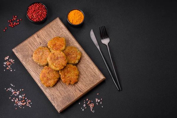 Delicious hearty vegetarian or vegan dish in the form of cutlets or patties consisting of potatoes, carrots, onions and beans on a dark concrete background
