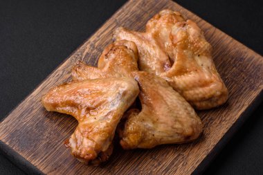 Baked chicken wings with salt, spices and herbs on a dark concrete background