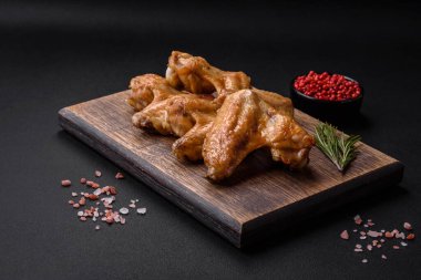 Baked chicken wings with salt, spices and herbs on a dark concrete background