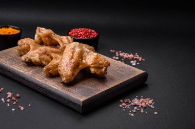 Baked chicken wings with salt, spices and herbs on a dark concrete background