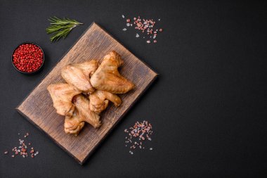 Baked chicken wings with salt, spices and herbs on a dark concrete background