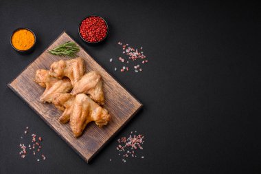 Baked chicken wings with salt, spices and herbs on a dark concrete background