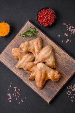 Baked chicken wings with salt, spices and herbs on a dark concrete background