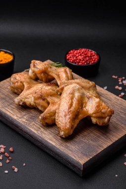 Baked chicken wings with salt, spices and herbs on a dark concrete background