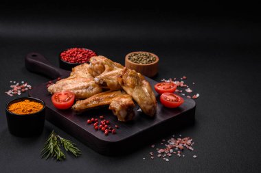 Baked chicken wings with salt, spices and herbs on a dark concrete background