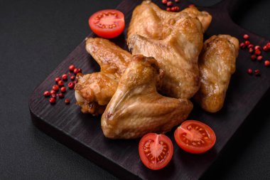 Baked chicken wings with salt, spices and herbs on a dark concrete background