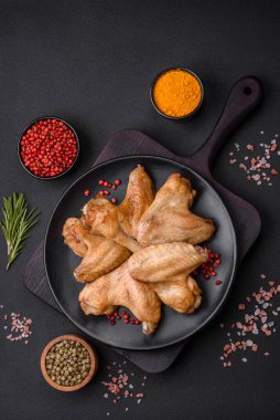 Baked chicken wings with salt, spices and herbs on a dark concrete background