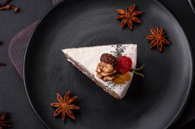 Delicious beautiful piece of cake with cream and berries on a black ceramic plate on a dark concrete background