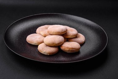 Delicious fresh baked cornmeal shortcakes or cookies on a black ceramic plate on a dark concrete background