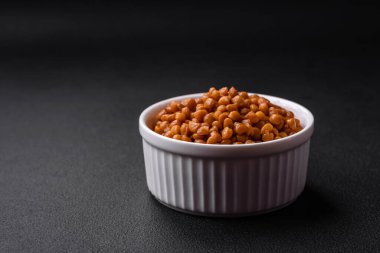 Lezzetli sağlıklı konserve mercimekler seramik bir kaburgalı beyaz kase üzerinde koyu beton arka planda