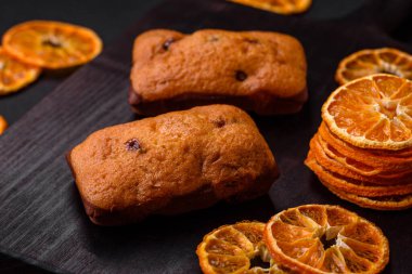 Lezzetli çikolatalı kekler ve koyu dokuda parlak turuncu renkli mandalina dilimleri.