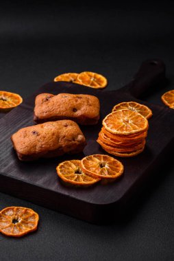 Lezzetli çikolatalı kekler ve koyu dokuda parlak turuncu renkli mandalina dilimleri.