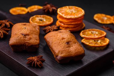 Lezzetli çikolatalı kekler ve koyu dokuda parlak turuncu renkli mandalina dilimleri.