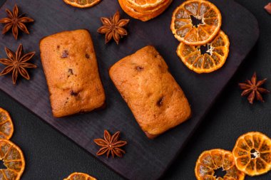 Lezzetli çikolatalı kekler ve koyu dokuda parlak turuncu renkli mandalina dilimleri.