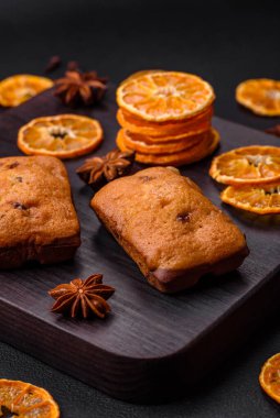 Lezzetli çikolatalı kekler ve koyu dokuda parlak turuncu renkli mandalina dilimleri.