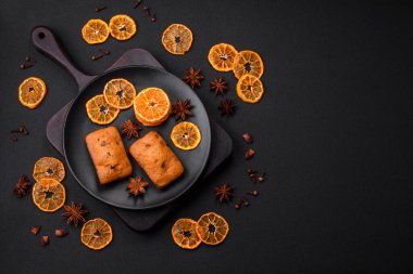 Lezzetli çikolatalı kekler ve koyu dokuda parlak turuncu renkli mandalina dilimleri.