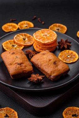 Lezzetli çikolatalı kekler ve koyu dokuda parlak turuncu renkli mandalina dilimleri.