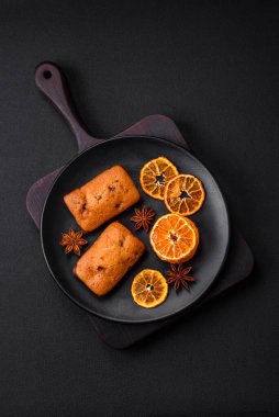 Lezzetli çikolatalı kekler ve koyu dokuda parlak turuncu renkli mandalina dilimleri.