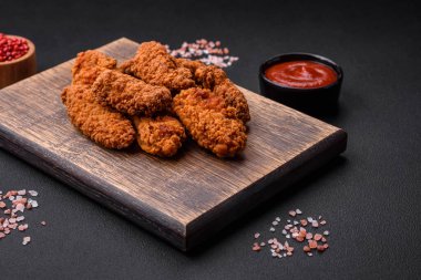 Lezzetli gevrek tavuk kanatları. Koyu beton bir arka planda baharat ve otlarla ızgara.