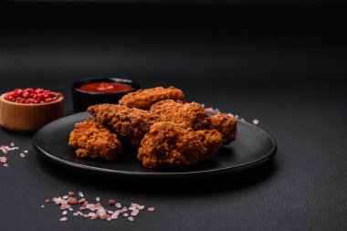 Lezzetli gevrek tavuk kanatları. Koyu beton bir arka planda baharat ve otlarla ızgara.