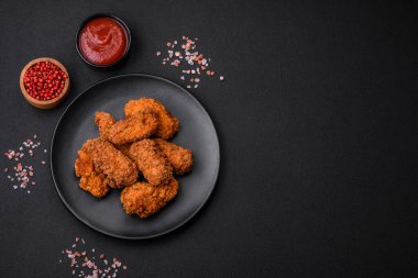 Lezzetli gevrek tavuk kanatları. Koyu beton bir arka planda baharat ve otlarla ızgara.