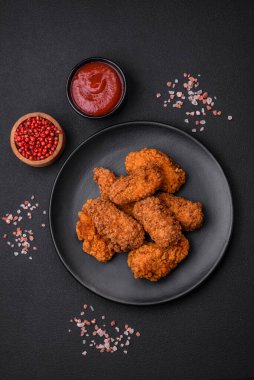 Lezzetli gevrek tavuk kanatları. Koyu beton bir arka planda baharat ve otlarla ızgara.