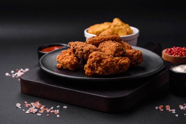 Lezzetli gevrek tavuk kanatları. Koyu beton bir arka planda baharat ve otlarla ızgara.