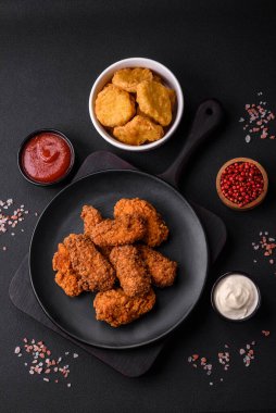 Lezzetli gevrek tavuk kanatları. Koyu beton bir arka planda baharat ve otlarla ızgara.
