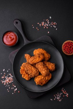 Lezzetli gevrek tavuk kanatları. Koyu beton bir arka planda baharat ve otlarla ızgara.