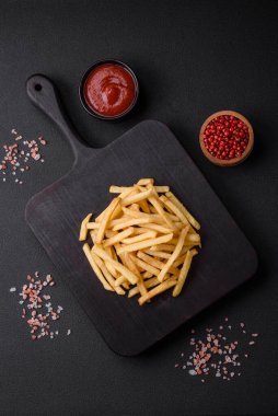Koyu beton zeminde tuzlu ve baharatlı çıtır patates kızartması. Sağlıksız yemek, fast food