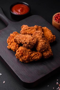 Lezzetli gevrek tavuk kanatları. Koyu beton bir arka planda baharat ve otlarla ızgara.