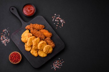 Koyu beton arka planda tuz ve baharatlı çıtır tavuk nuggetları. Abur cubur, fast food