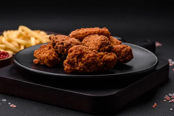 stock image Delicious crispy breaded chicken wings grilled with spices and herbs on a dark concrete background