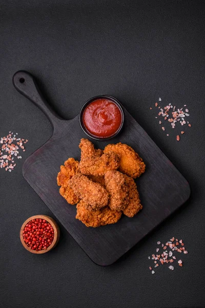 stock image Delicious crispy breaded chicken wings grilled with spices and herbs on a dark concrete background