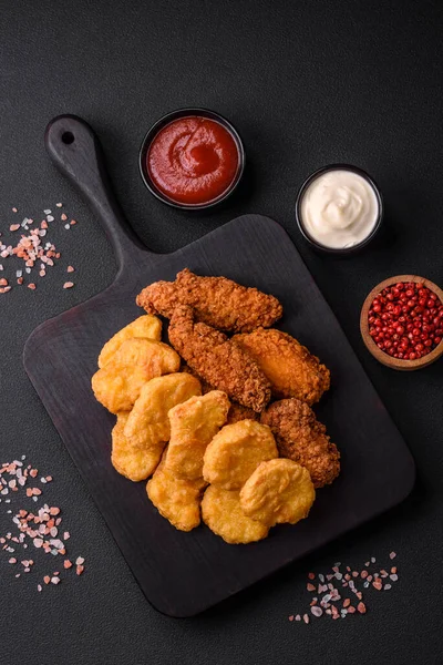 stock image Delicious crispy chicken nuggets with salt and spices on a dark concrete background. Junk food, fast food