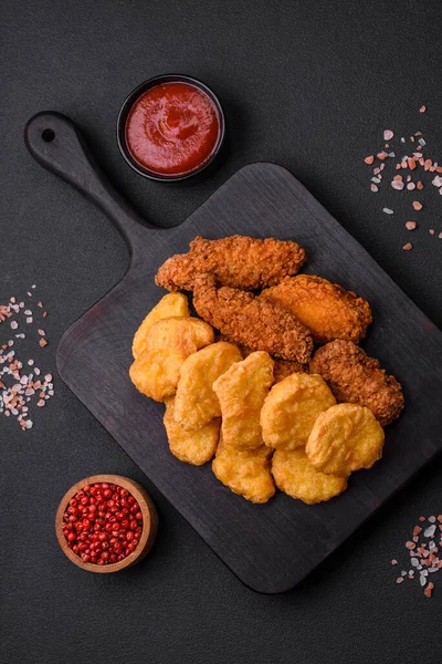 stock image Delicious crispy chicken nuggets with salt and spices on a dark concrete background. Junk food, fast food