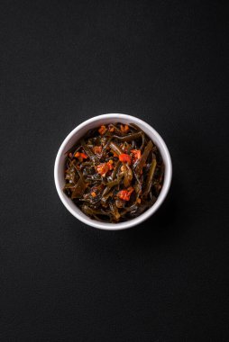 Koyu beton arka planda kırmızı biber, baharat ve tuz ile marine edilmiş lezzetli deniz yosunu. Lezzetli vejetaryen salatası