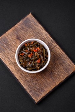 Koyu beton arka planda kırmızı biber, baharat ve tuz ile marine edilmiş lezzetli deniz yosunu. Lezzetli vejetaryen salatası