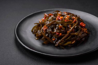 Koyu beton arka planda kırmızı biber, baharat ve tuz ile marine edilmiş lezzetli deniz yosunu. Lezzetli vejetaryen salatası