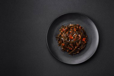 Koyu beton arka planda kırmızı biber, baharat ve tuz ile marine edilmiş lezzetli deniz yosunu. Lezzetli vejetaryen salatası